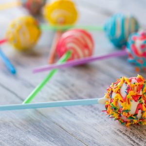 Bright candy on a stick. Cake pop with icing. How to make children happier. White chocolate and cream filling.