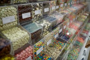 food, junk-food, sell, confectionery and unhealthy eating concept - different sweets in transparent plastic boxes at candy shop